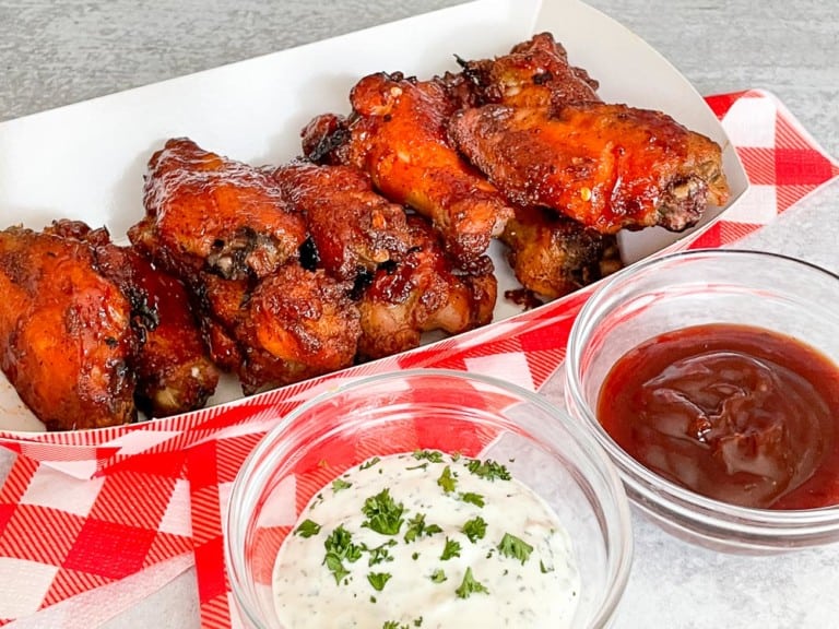 Spicy wings in a paper basket and with dips in bowls.
