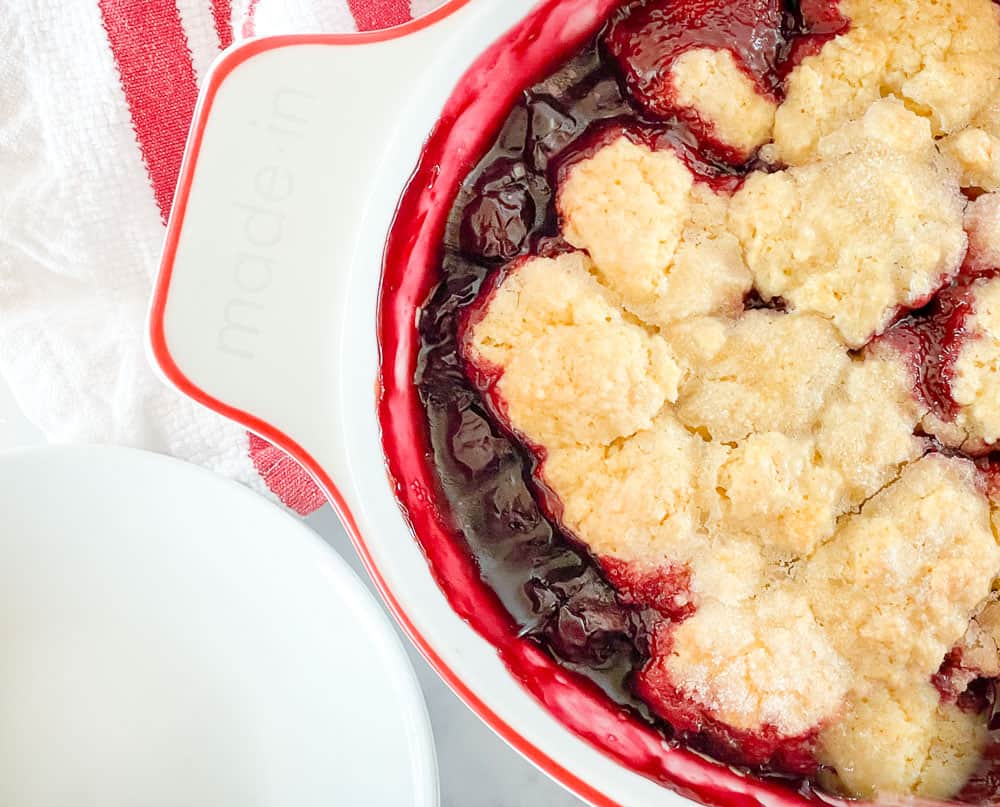 Cherry cobbler in a baking dish with plates.