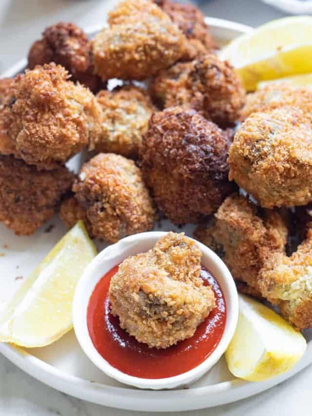 Fried calamari with ketchup and lemon wedges on a white plate.