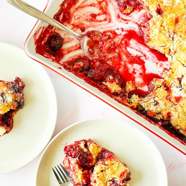 Two plates of cherry dump cake and a 9x13 pan of cake.