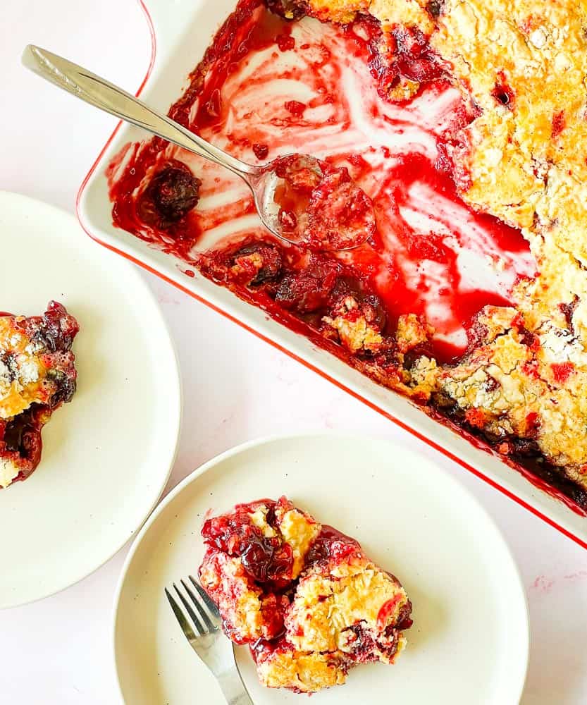 Two plates of cherry dump cake and a 9x13 pan of cake.