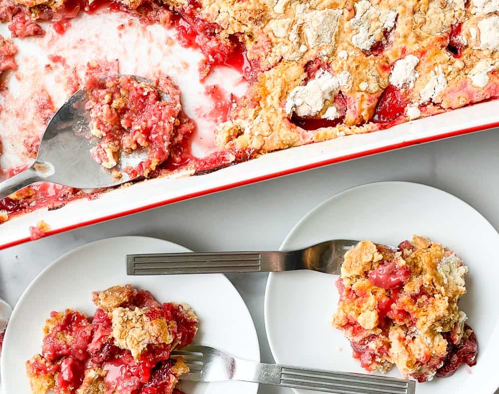 Two serving of strawberry dump cake with the rest of it on the side.