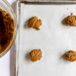 Scoops of cookie batter are placed on a baking sheet.