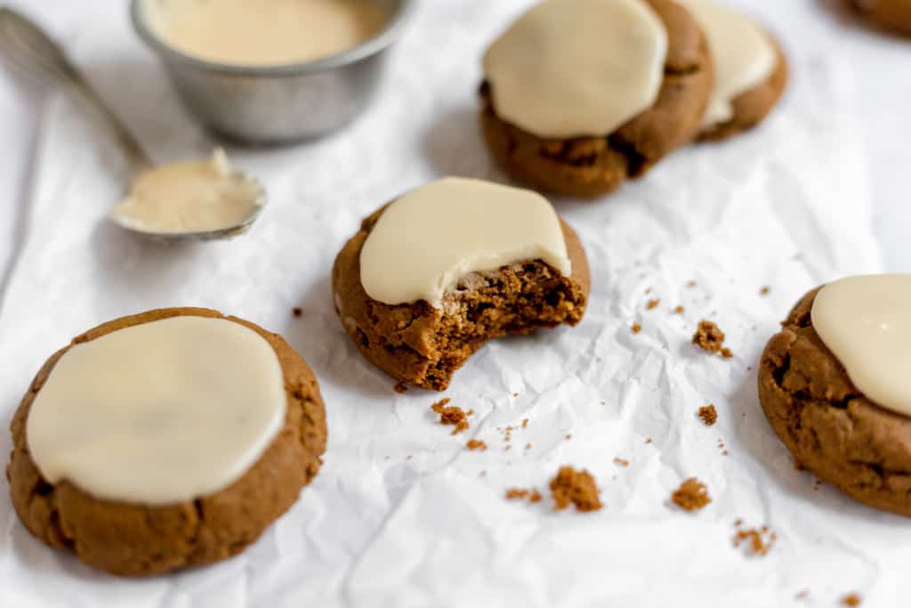 An iced molasses cookie with a bite taken out of it.