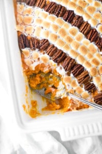 Side dish for thanksgiving with sweet potatoes with lines of alternating candied pecans and mini marshmallows.