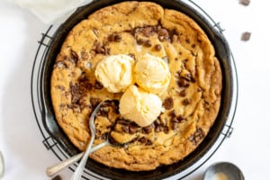 Pizookie with ice cream and spoons in a cast-iron skillet.