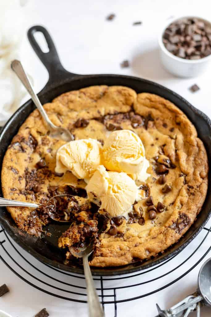 Pizookie with ice cream and spoons in a cast-iron skillet. 