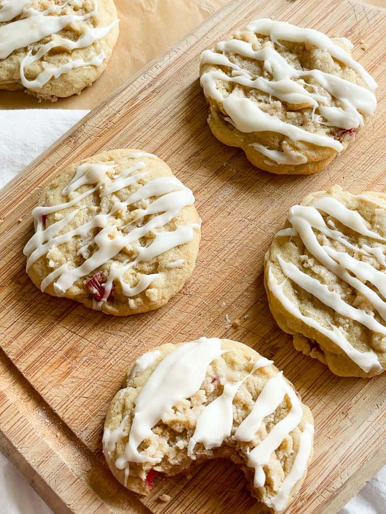 Cookies drizzled with icing, one has a bite taken from it. 