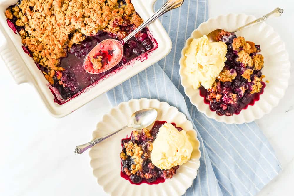 Blueberry crisp in a pan and on plates with ice cream.