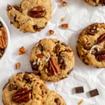 Brown butter cowboy cookies with pecans and chocolate chunks on a [parchment paper.