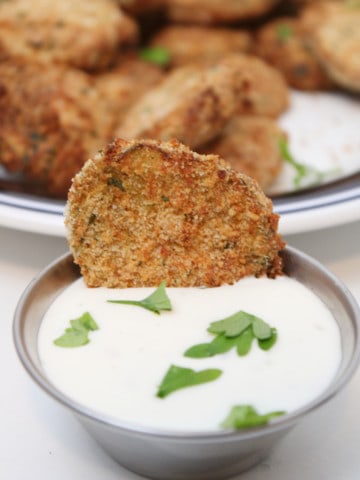 Dipping fried pickles in a dip or dressing.