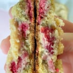 White chocolate chip cookie with raspberries broken in half to show the inside.