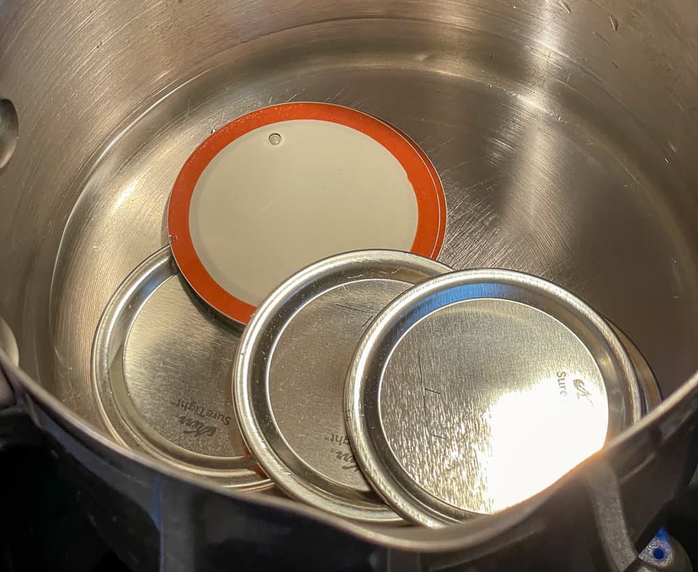 Washed flat lids in hot water for water bath canning.