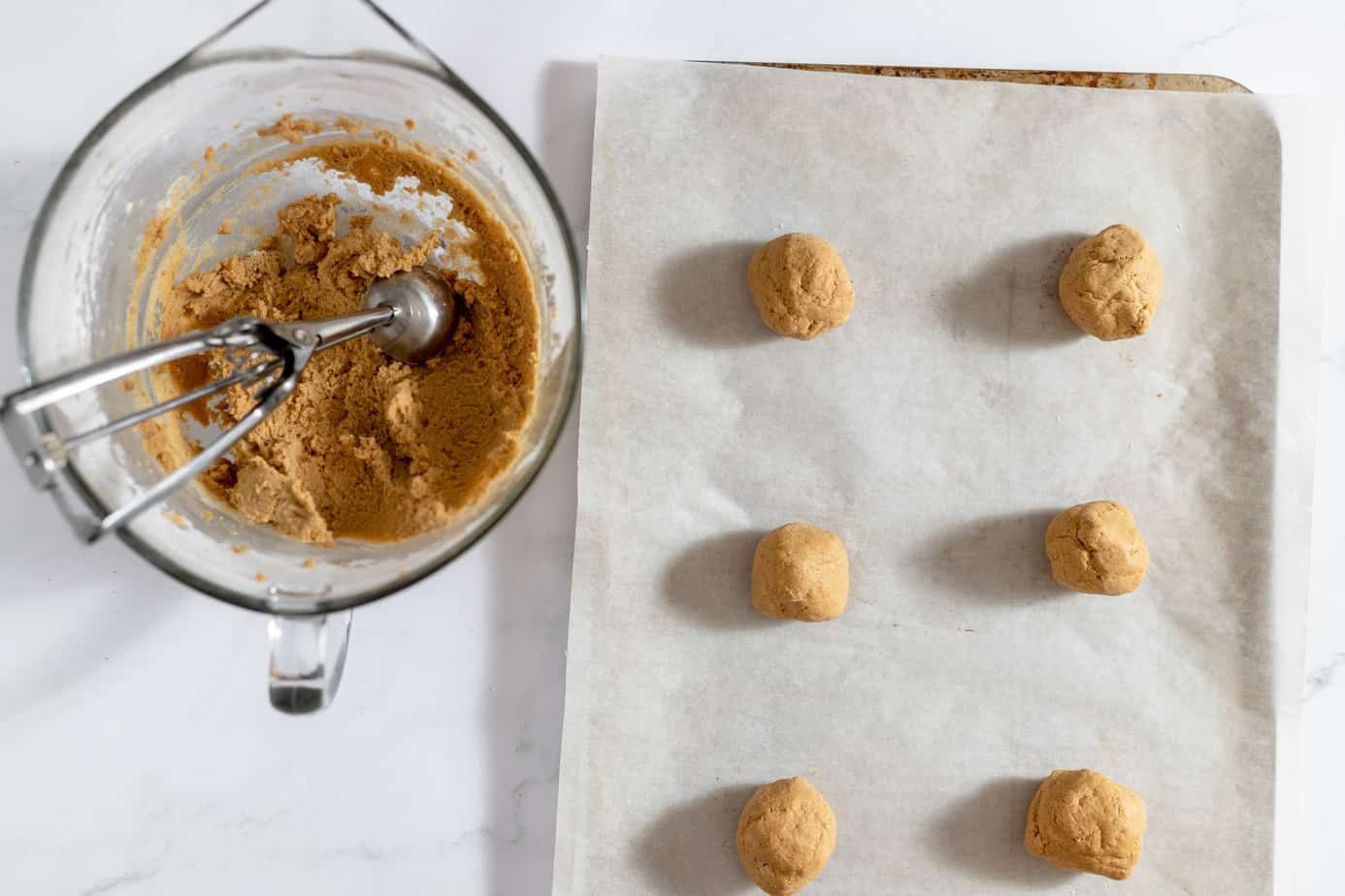 Scooping cookie dough and placing on a cookie sheet.
