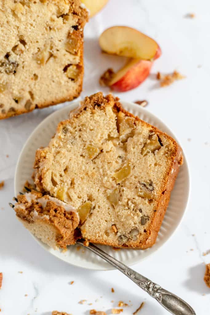 A slice of apple bread with a fork on a plate.