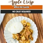 A serving of Easy Apple Crisp with a scoop of vanilla ice cream on a white plate, placed on a wooden surface with a spoon beside it.