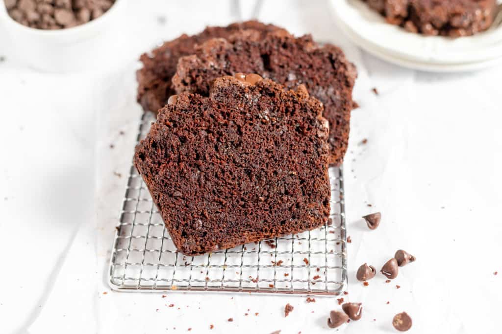 Slices of double chocolate zucchini bread with chocolate chips on the side.