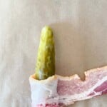 Wrapping bacon around a dill pickle spear.