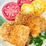 Crispy panko chicken made in the air fryer on a plate with hrebs and tomatoes.