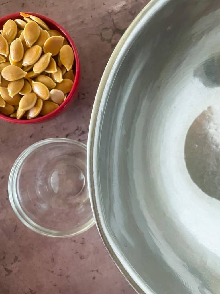 Pumpkin seeds, oil, and a bowl for roasting seeds. 