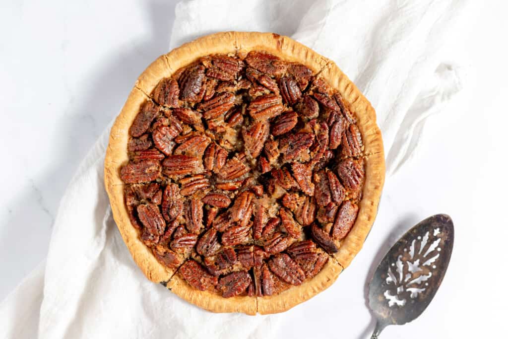 Perfectly baked bourbon pecan pie with a pie server next to it.
