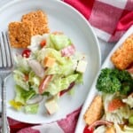 A plate of antipasto salad with a fork next to a napkin and the salad platter.