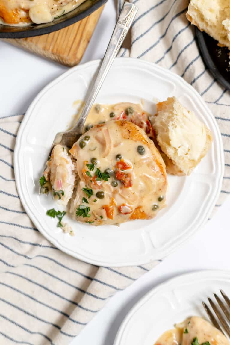 A serving of easy chicken piccata served with a piece of bread.