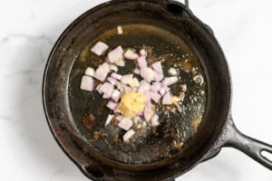 Adding shallots and garlic to the cooking pan.