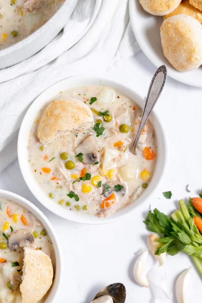 Half eaten biscuit on top of a bowl of chicken soup.