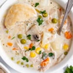 Chicken pot pie soup in a bowl with a biscuit on top.