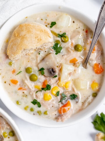 Chicken pot pie soup in a bowl with a biscuit on top.