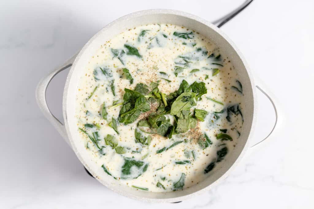 A bowl of chicken and gnocchi soup with a spoon in it.