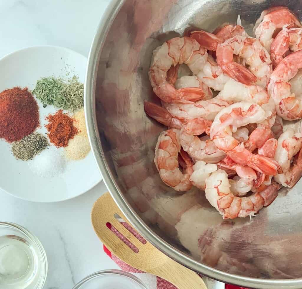 Ingredients for cajun shrimp in bowls on a table.