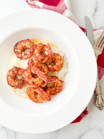 Cajun shrimp over creamy grits in a bowl with butter.
