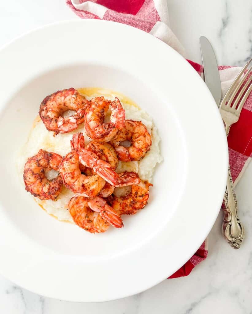 Cajun shrimp over creamy grits in a bowl with butter.