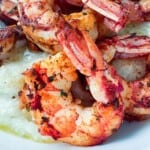 Zesty spicy shrimp over grits or polenta in a serving bowl.