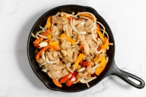 Cast iron skillet with fajitas in to bake in the oven.
