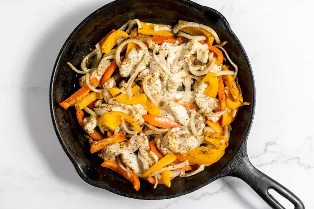 Chicken and peppers in a skillet for the post How to Season cast iron like a pro. 