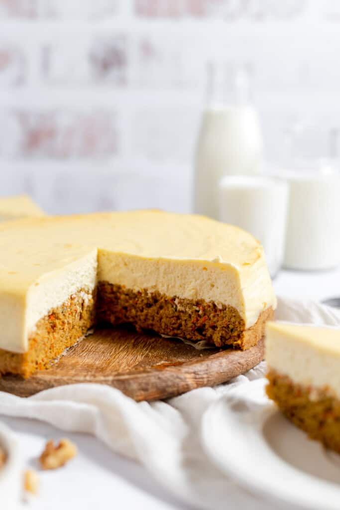 Carrot Cake Cheesecake with 2 slices out of it with milk in the background. 