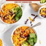 Bowls of Chicken Taco Soup topped with shredded cheese, tortilla strips, cilantro, and avocado slices sit on a white surface, next to a cutting board with fresh avocado.