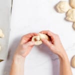 Hands tying the fresh dough into knots for garlic knots.
