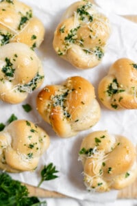 Finished garlic knots covered in herbs, butter and cheese.