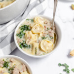 Sausage Tortellini Soup in soup bowls with spoons.