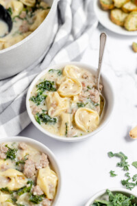 Sausage Tortellini Soup in soup bowls with spoons.