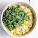 Kale and tortellini added to the diuch oven for sausage tortellini soup.