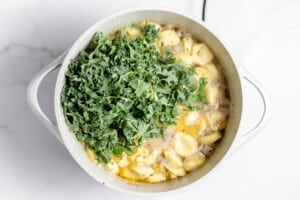 Kale and tortellini added to the diuch oven for sausage tortellini soup.