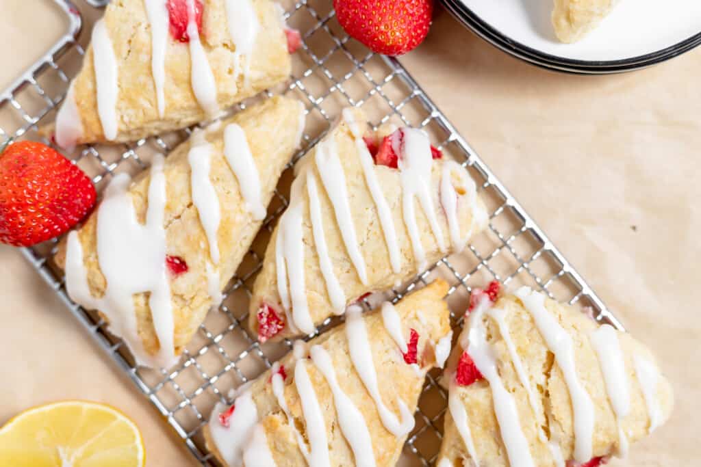 Strawberry scones drizzled with lemon glaze on a cooling tray.