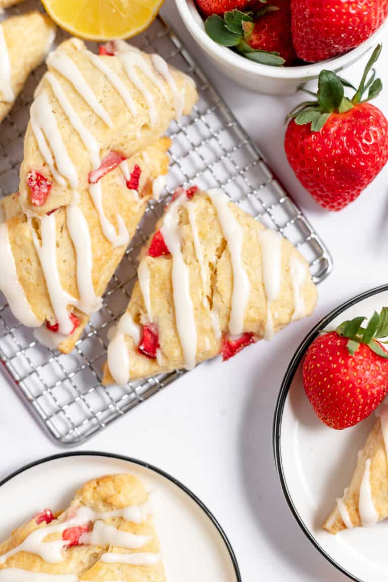 Strawberry scones on a cooling tray along with fresh strawberries.