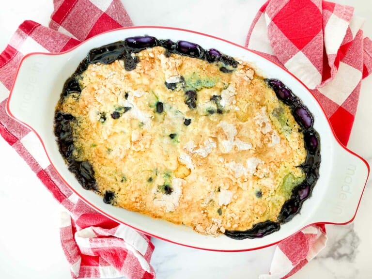 Blueberry Dump Cake in an oval baking dish on linens.