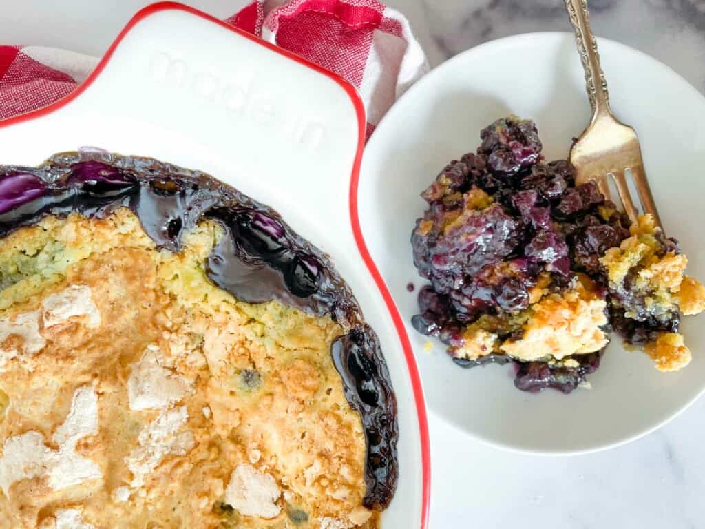 Blueberry dump cake on a plate and in the baking pan.